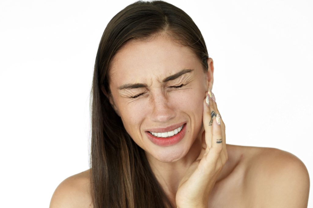 a mulher segura os dedos na bochecha mostrando dor de dente 1