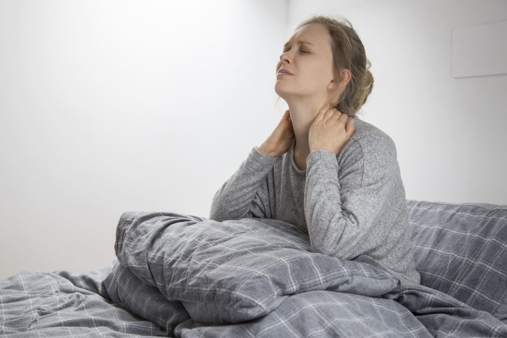 cansada mulher doente na cama tocando seu pescoco sofrendo de dor 1 1